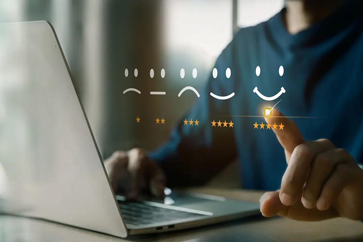 A man at a laptop checking a five star review with a happy face