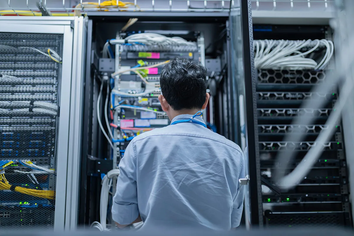 IT technician working at an open server rack in a data centre