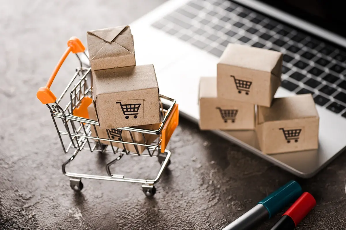 Miniature shopping in a trolly next to a laptop