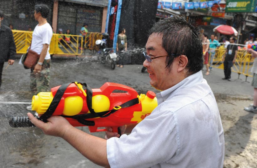 a wet thai man with a yellow and red water gun