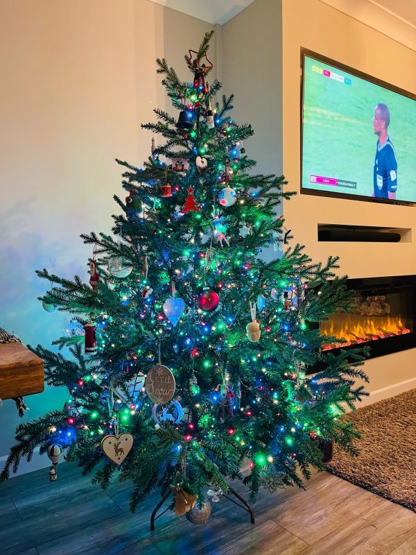 a decorated christmas tree with the world cup playing on a tv in the background